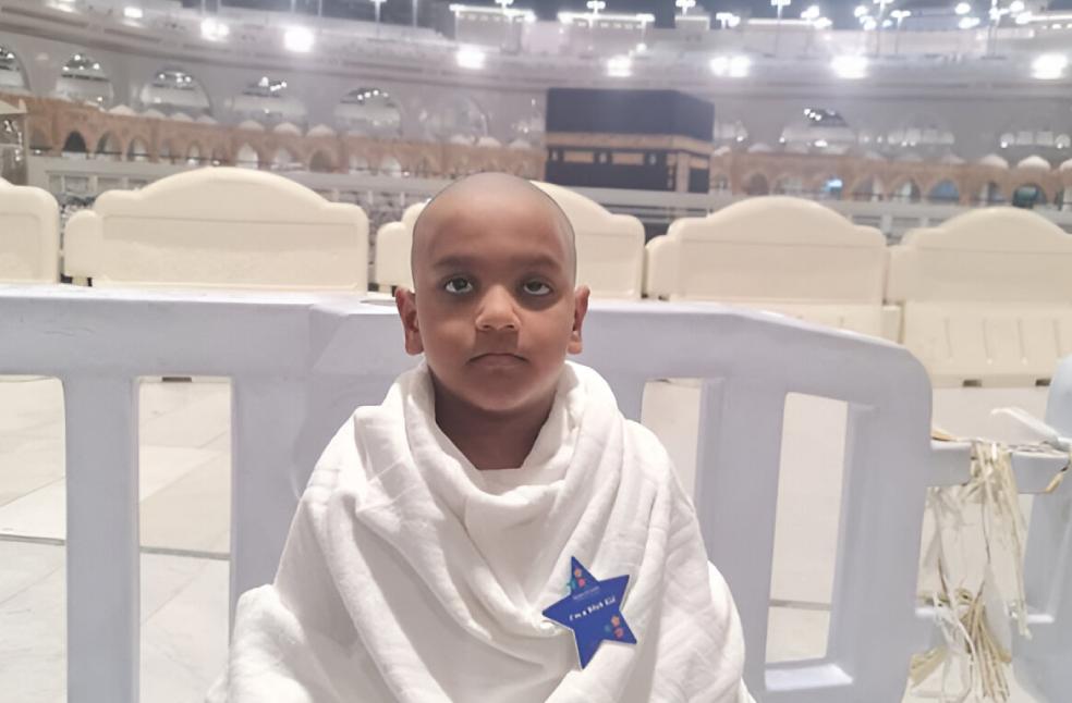 A Child Standing in front of Kabah after performing his Umrah